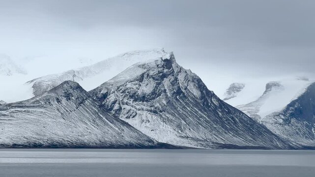 Witness the magnificence of Baffin Island coastal landscapes. The video captures impressive cliffs rising above calm blue waters, highlighting nature's raw beauty in a remote region.