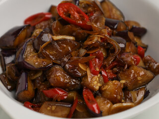 Stir fried eggplants with chili, garlic and onion on white bowl