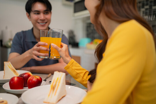 Asian couple happily enjoying healthy breakfast at home kitchen making juice toast celebrating togetherness morning lifestyle peaceful domestic scene
