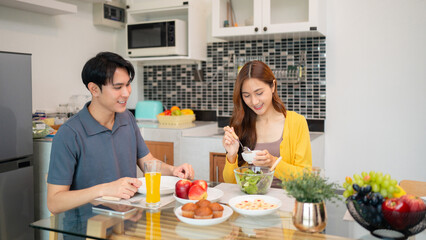 Asian adult couple enjoy healthy meal dining together at modern home kitchen table sharing happy relaxed lifestyle moments