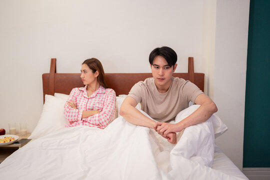 Asian young adult couple experiencing relationship conflict in bedroom morning after argument emotional distance communication problem domestic disagreement