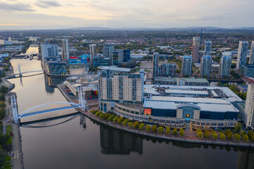 Aerial view over Salford Quays waterfront at twilight with calm reflections and modern architecture.