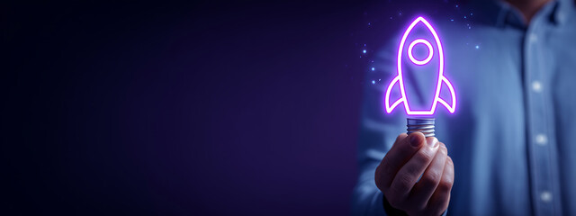 Businessman holds an illuminated light bulb with a neon purple rocket icon