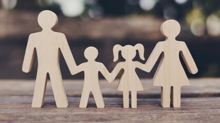 A photograph of wooden family figurines arranged in a line on a weathered wooden surface.