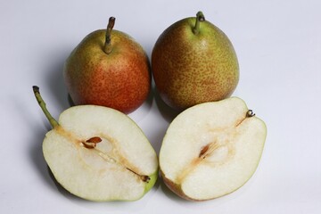 closeup of fresh pears, two whole and one cut in half, showing the flesh and seeds