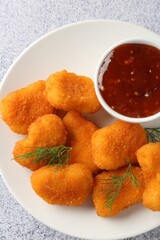 Tasty chicken nuggets with sauce on light grey table, top view