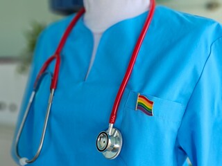 Medical professional in blue scrubs with a rainbow badge lgbt and stethoscope during a healthcare
