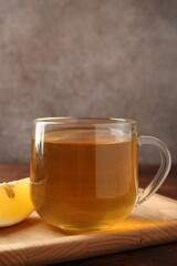 Aromatic tea in cup with lemon on wooden table, closeup