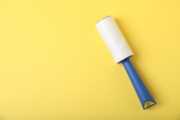 One lint roller on yellow background, top view. Space for text