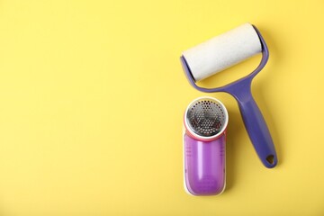 Lint roller and fabric shaver on yellow background, flat lay. Space for text
