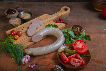 Meat delicacies on a wooden table in the kitchen among greens and vegetables
