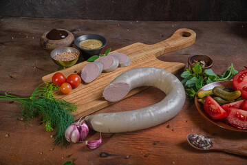 Meat delicacies on a wooden table in the kitchen among greens and vegetables