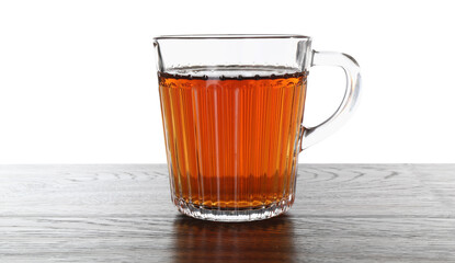 Cup of aromatic black tea on dark wooden table against white background
