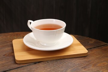 Aromatic black tea in cup on wooden table, closeup