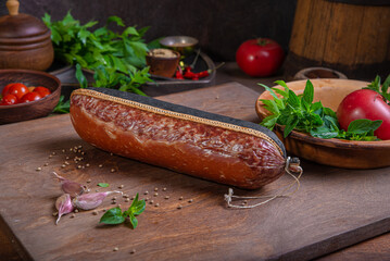 Meat delicacies on a wooden table in the kitchen among greens and vegetables