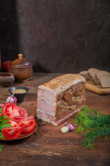 Meat delicacies on a wooden table in the kitchen among greens and vegetables