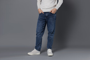Man in stylish jeans on grey background, closeup