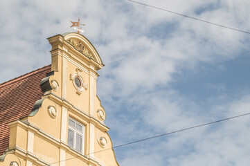 Giebelständiger Satteldachbau mit Neurenaissancefassade mit Sprossenfenstern und Wetterfahne am Weinmarkt in Nördlingen vor blauem Himmel mit Wolken