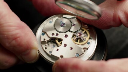 Close-up view of a watchmaker's hands assembling intricate watch mechanisms on a workbench