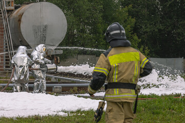 Firefighters in protective clothing use a foam generator to supply foam to extinguish the fire....