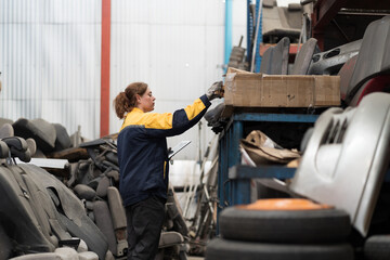 Automotive spare parts warehouse or auto parts warehouse. Female warehouse worker inspected spare parts in auto parts warehouse, using digital tablet check inventory in workplace