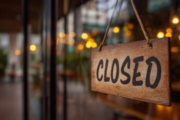 Small business cafe with CLOSED sign in focus on glass entrance, blurred empty interior behind