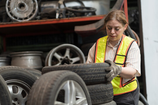 Automotive spare parts warehouse or auto parts warehouse. Female warehouse worker inspected wheel or tire in auto parts warehouse, using digital tablet check inventory in workplace