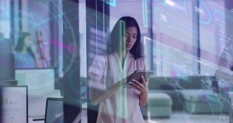 Holding tablet businesswoman analyzing data behind glass partition at office with digital overlays