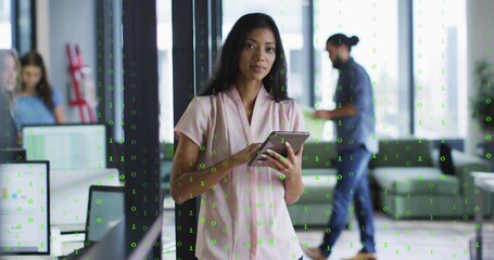 Worker wearing pink blouse holding tablet near glass partition in office, with green binary overlay