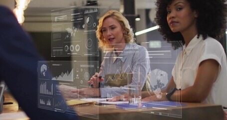 Two colleagues in business attire reviewing documents and interacting with data displays in office