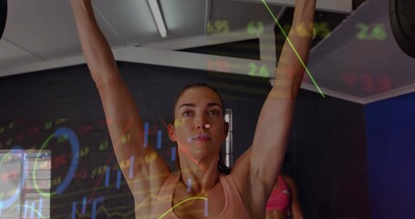 Mid adult lifter in pink sportswear lifting barbell overhead in gym, with graph overlays