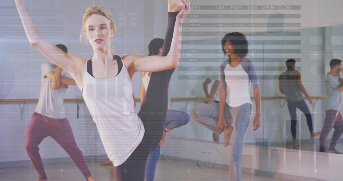 Fototapeta Instructor leading group by performing leg-and-arm stretch in studio, with wooden barre and mirror