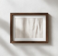 A simple, elegant framed artwork featuring a textured, neutral fabric against a light wall, creating a minimalist aesthetic.
