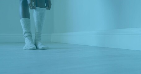 Moving woman's hands sliding sock over calf in empty room, with ribbed knit sock, copy space