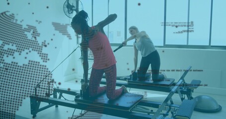 Two women kneeling on reformers exercising in pilates studio with BOSU trainer, copy space