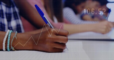 Writing child holding blue ballpoint pen and wearing beaded bracelets at school desk, lined paper