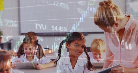 Guiding teacher wearing pink blouse leaning over braided girl using tablet at school, stock chart