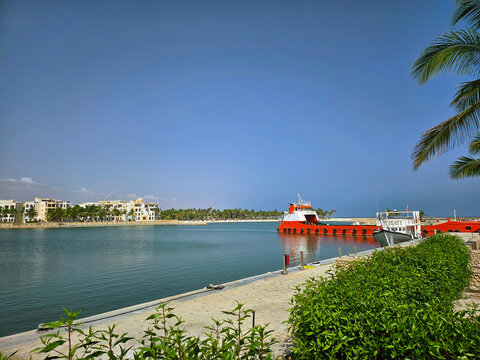 Calm marina lagoon with red workboat near Salalah (Hawana area), Oman