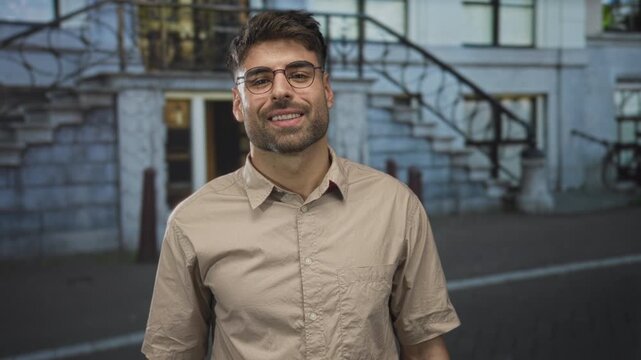 Man with glasses and scruffy beard pointing his fist toward the viewer on a city street; confidence bond.