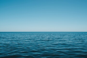 Obraz premium Calm blue sea meets the horizon under a vast clear sky capturing tranquil seascape beauty
