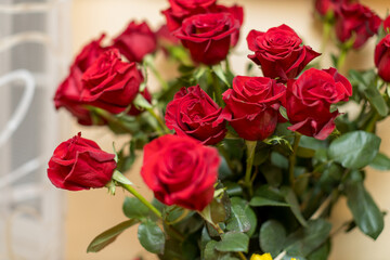 A stunning bouquet of fresh red roses, featuring open blooms and green foliage, is captured in close detail.