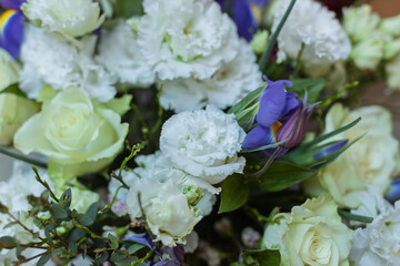 A beautiful floral arrangement features fresh white eustoma, delicate light green roses, and striking purple iris blooms with lush green foliage.