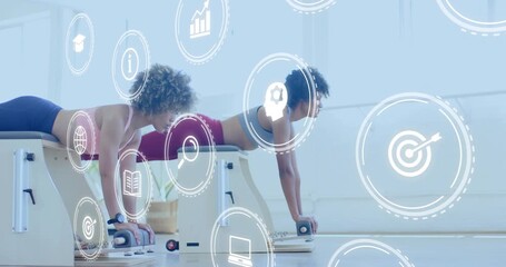 Partners gripping reformers and holding plank activating swirling icons visualizing fitness metrics - Powered by Adobe