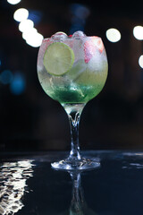 Refreshing cocktail with lime and strawberry in an elegant glass against a blurred night background