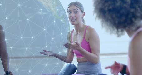Female speaker raising palm toward group on yoga mats initiating globe overlay in fitness class - Powered by Adobe