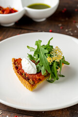Mini tomato tart topped with burrata and peppery arugula garnish