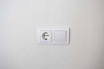  White electrical socket and light switch on a clean white wall. Minimal home interior design with neutral colors. Modern household detail and simple living concept. High quality photo