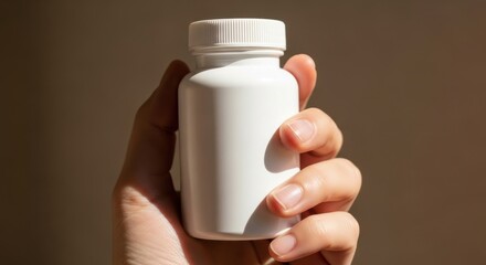 Hand holding a white medicine bottle with a white cap