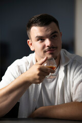 jeune homme dégustant un verre de cognac avec un plaisir visible