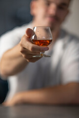 petit verre de cognac dnas la main d'un homme, tendre un verre d'alcool